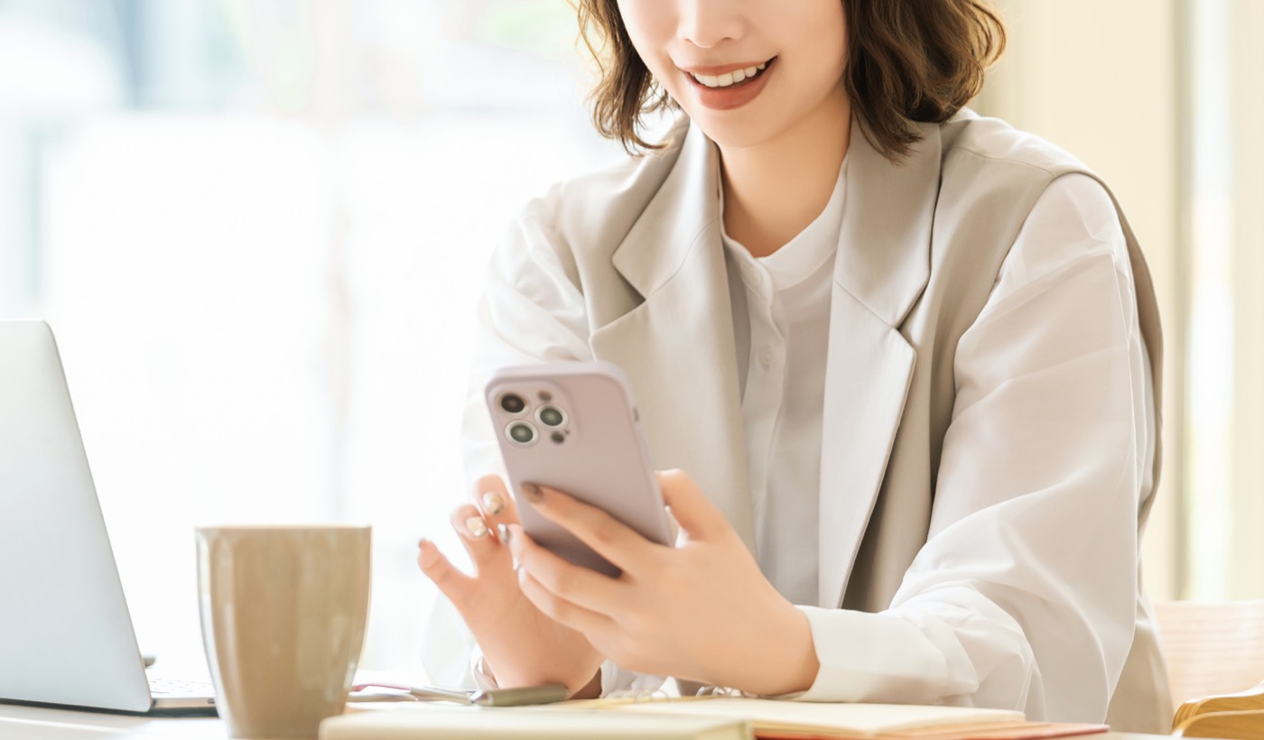 スマートフォンを見ながら笑顔の女性